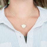 The picture shows a model wearing a yellow gold manta ray pendant with topaz.