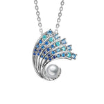 In this photo there is a small white gold ombre wave pendant with gradient blue aquamarine gemstones and one white south sea pearl.