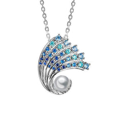 In this photo there is a small white gold ombre wave pendant with gradient blue aquamarine gemstones and one white south sea pearl.