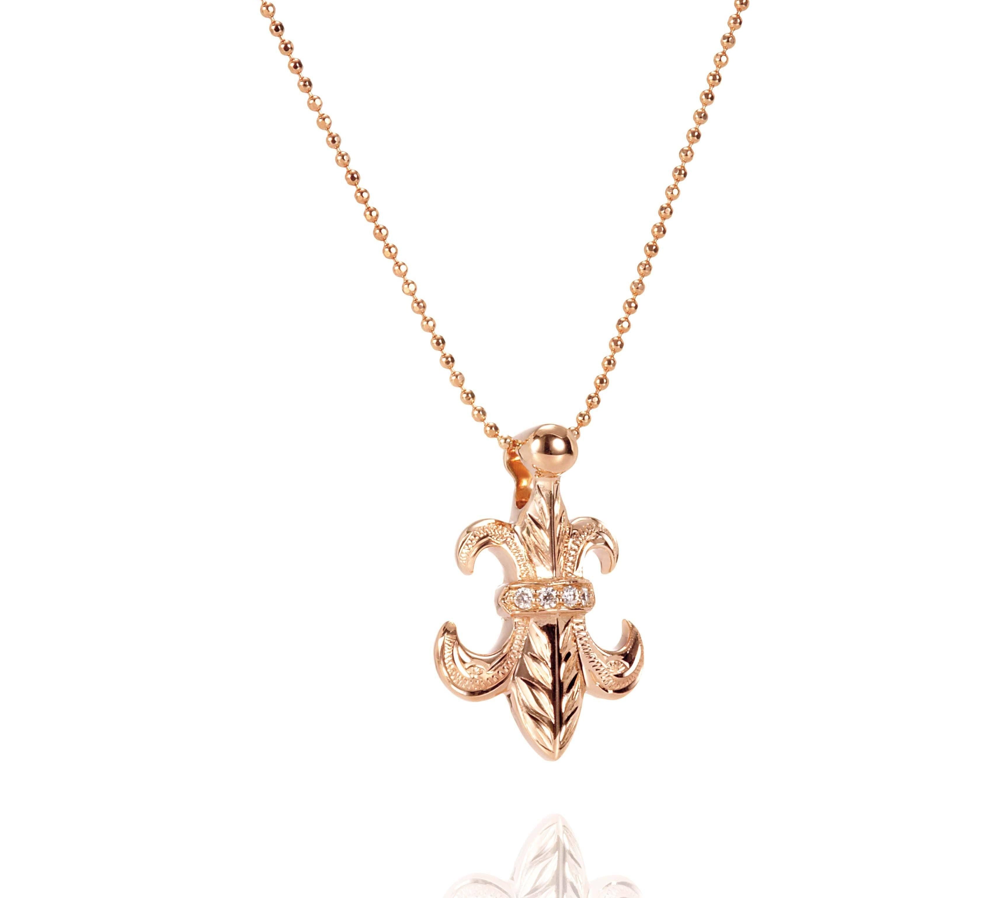 The picture shows a 14K yellow gold fleur-de-lis pendant with hand engravings.