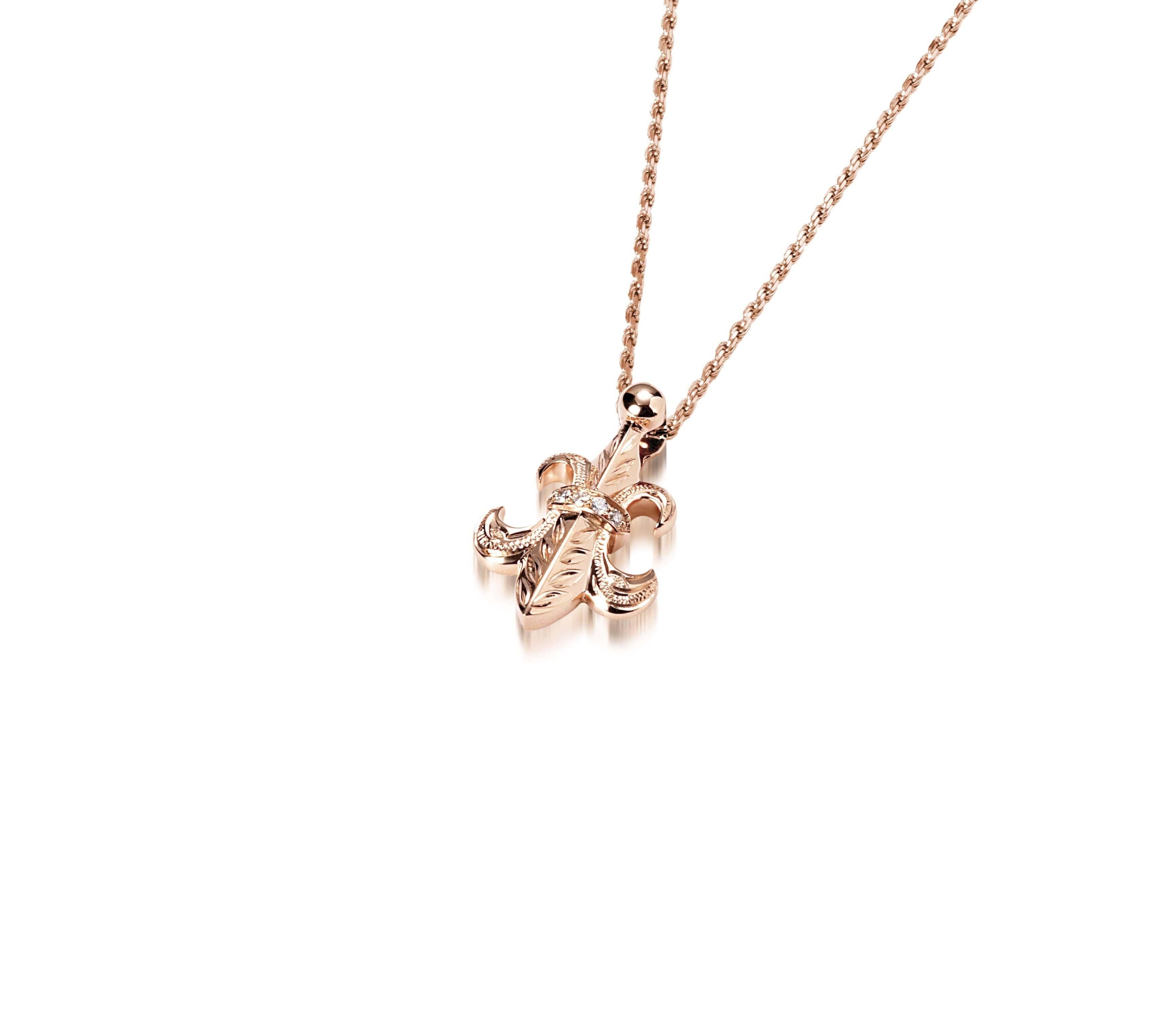 The picture shows a 14K yellow gold fleur-de-lis pendant with hand engravings.