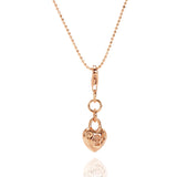 The picture shows a 14K rose gold heart lock charm with hand-engraved detailing.