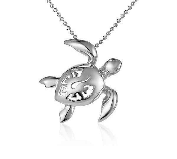 In this photo there is a white gold sea turtle necklace with a hibiscus flower cut-out.