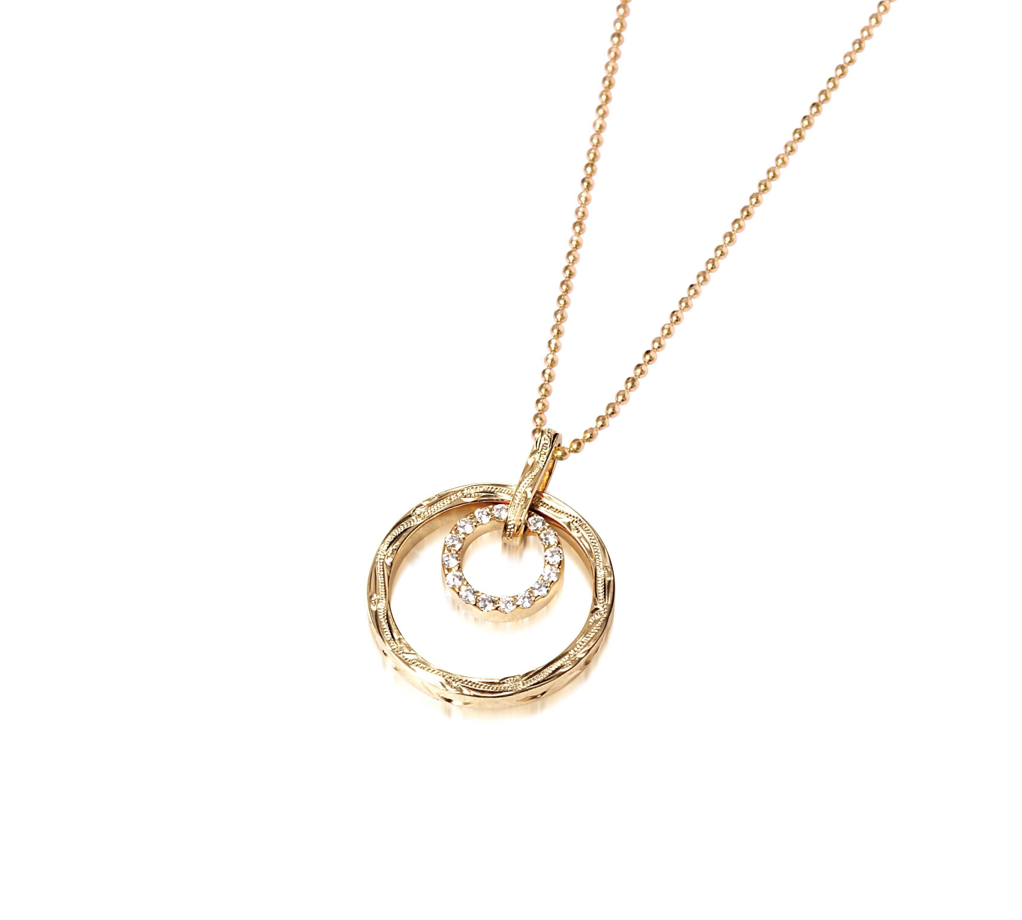 The picture shows a 14K yellow gold two circle infinity scroll pendant with hand engravings and diamonds.