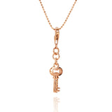 The picture shows a 14K yellow gold key charm with hand-engraved detailing.