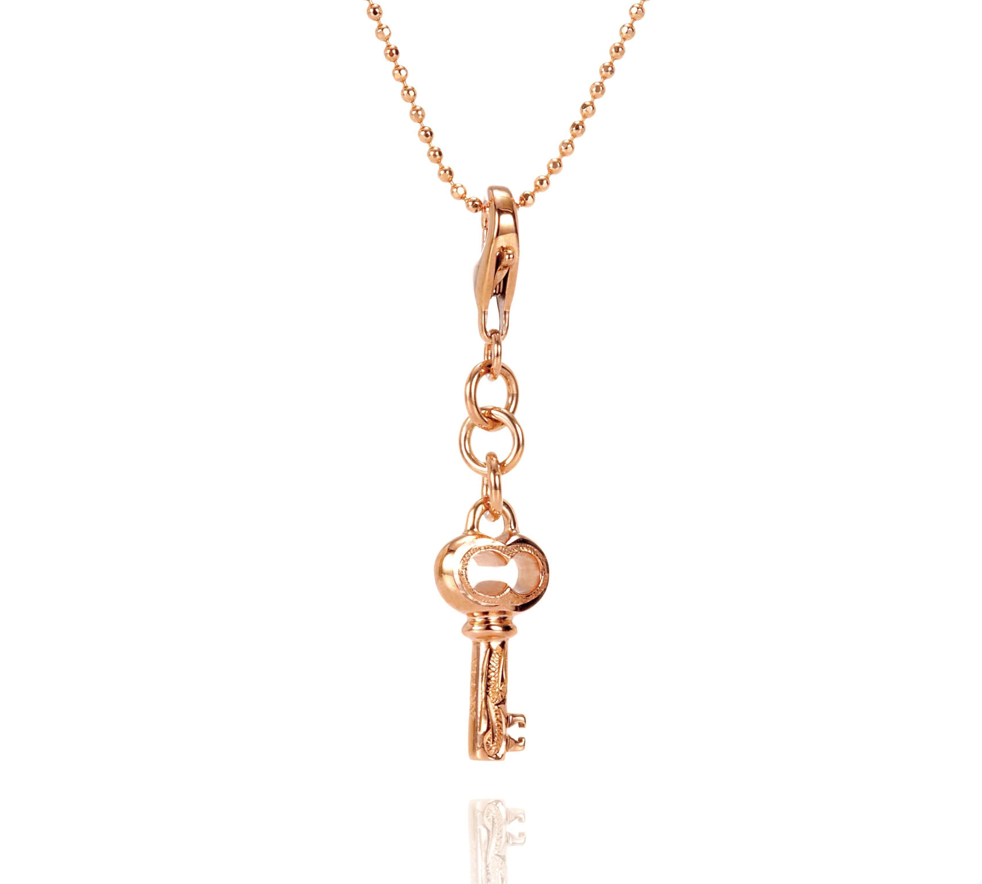 The picture shows a 14K yellow gold key charm with hand-engraved detailing.