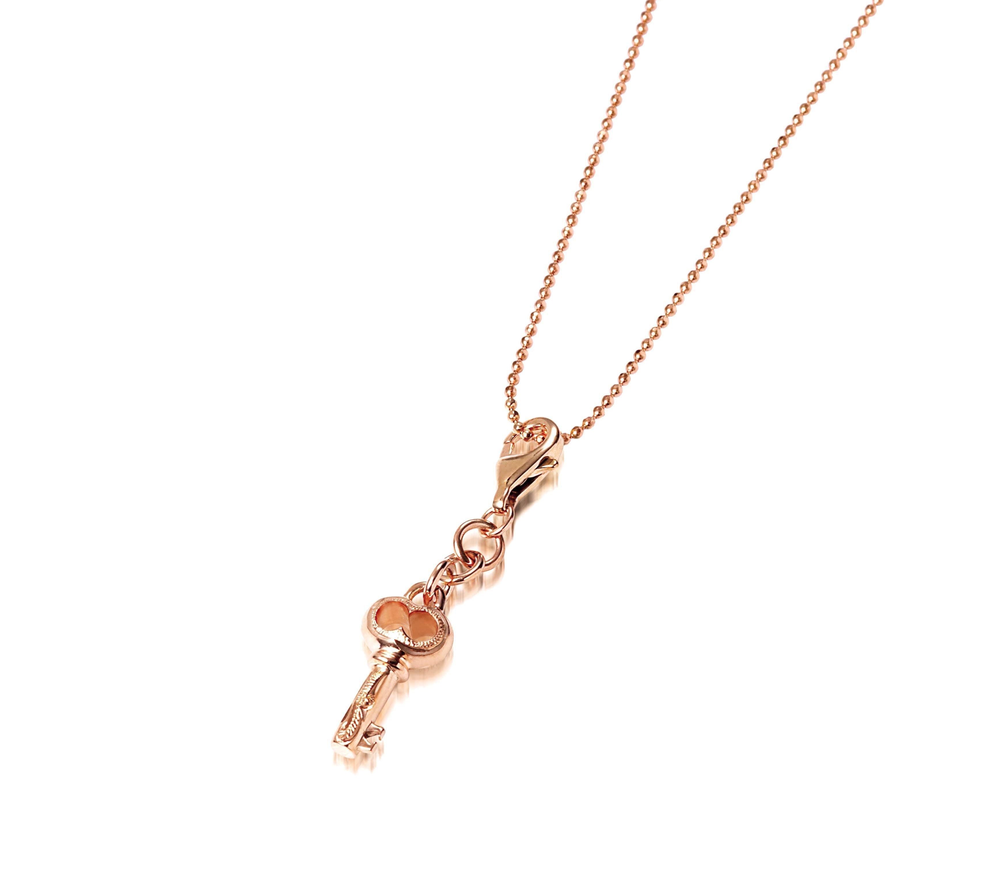 The picture shows a 14K yellow gold key charm with hand-engraved detailing.