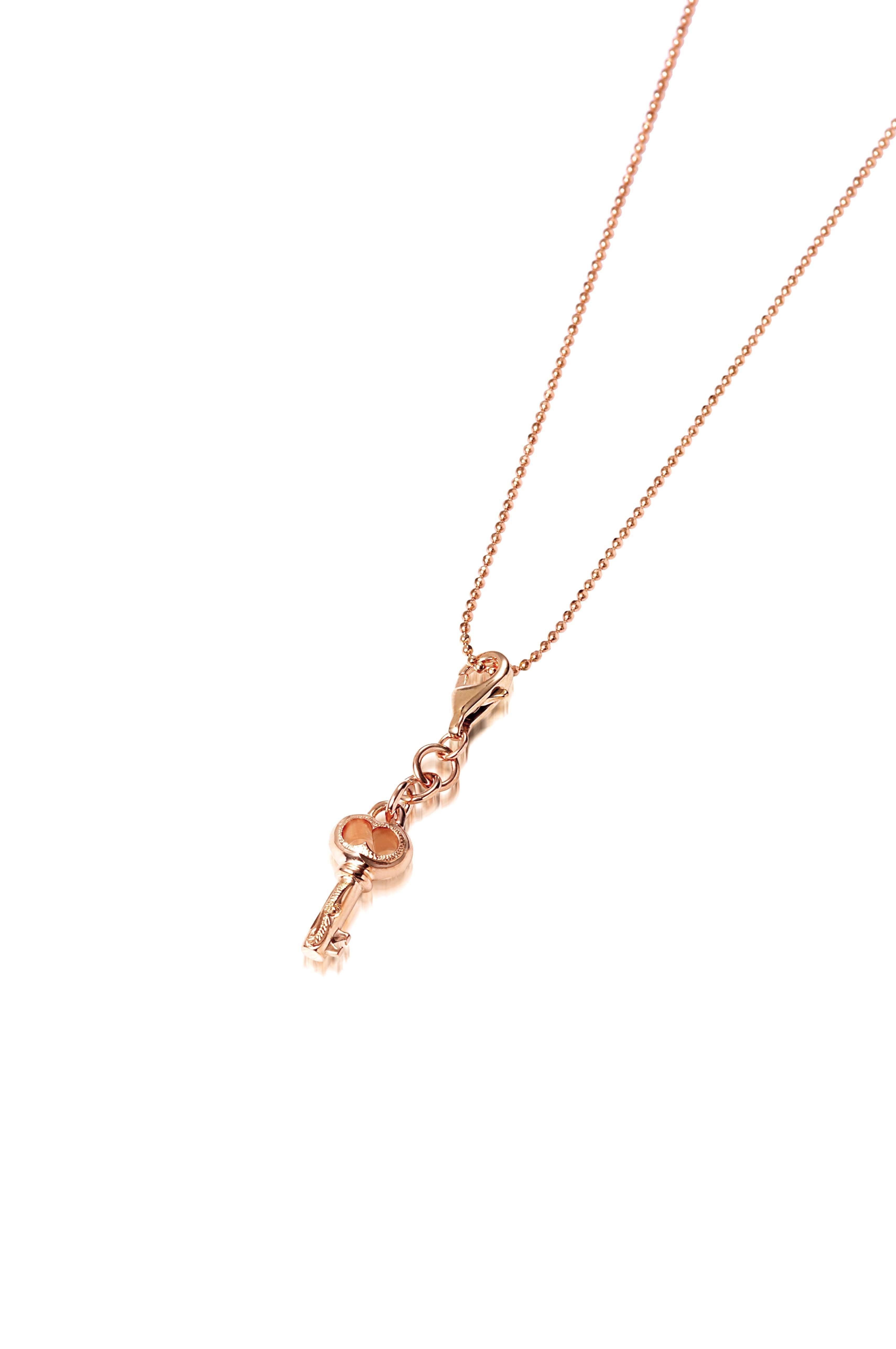 The picture shows a 14K yellow gold key charm with hand-engraved detailing.