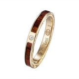 In this photo there is a yellow gold koa wood ring with hand engravings of scrolls and one diamond.