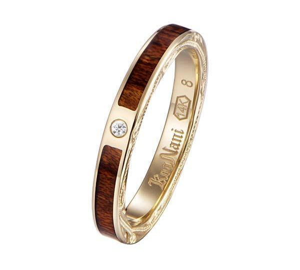 In this photo there is a yellow gold koa wood ring with hand engravings of scrolls and one diamond.