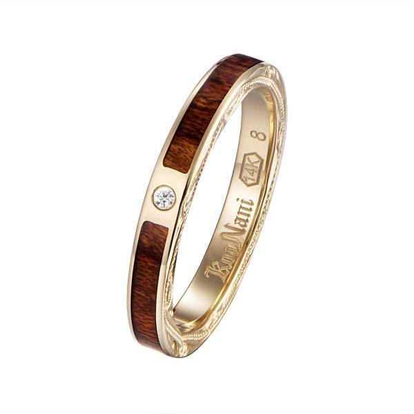 In this photo there is a yellow gold koa wood ring with hand engravings of scrolls and one diamond.