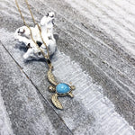 The picture shows a 14K yellow gold sea turtle pendant with a larimar gemstone.