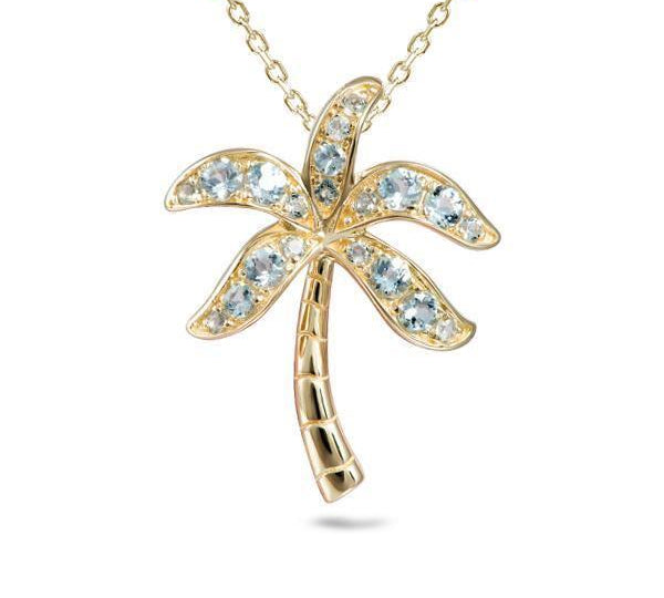 In this photo there is a yellow gold palm tree pendant with aquamarine gemstones.