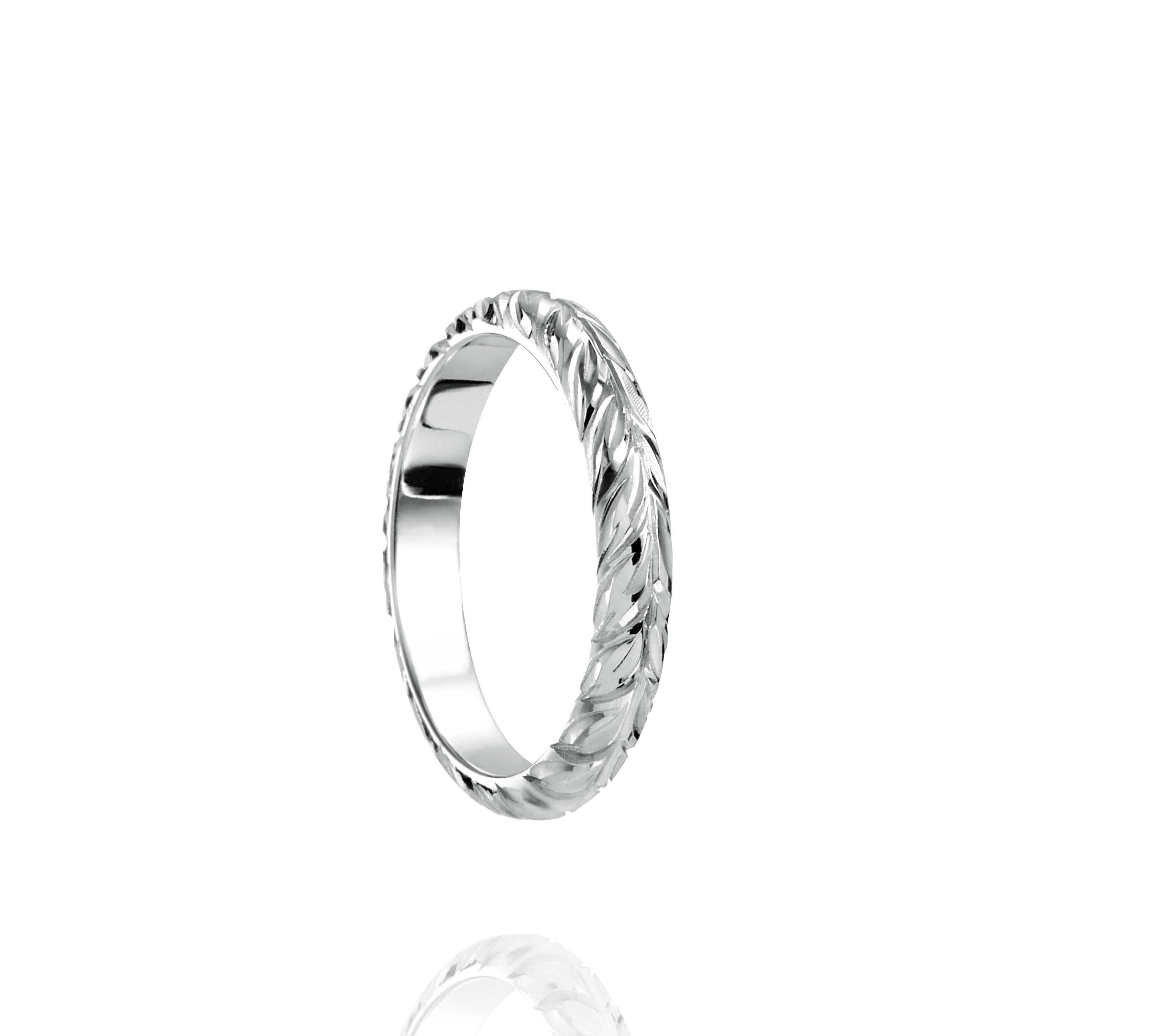 In this photo there is a white gold lei ring with hand engravings of a maile leaf.