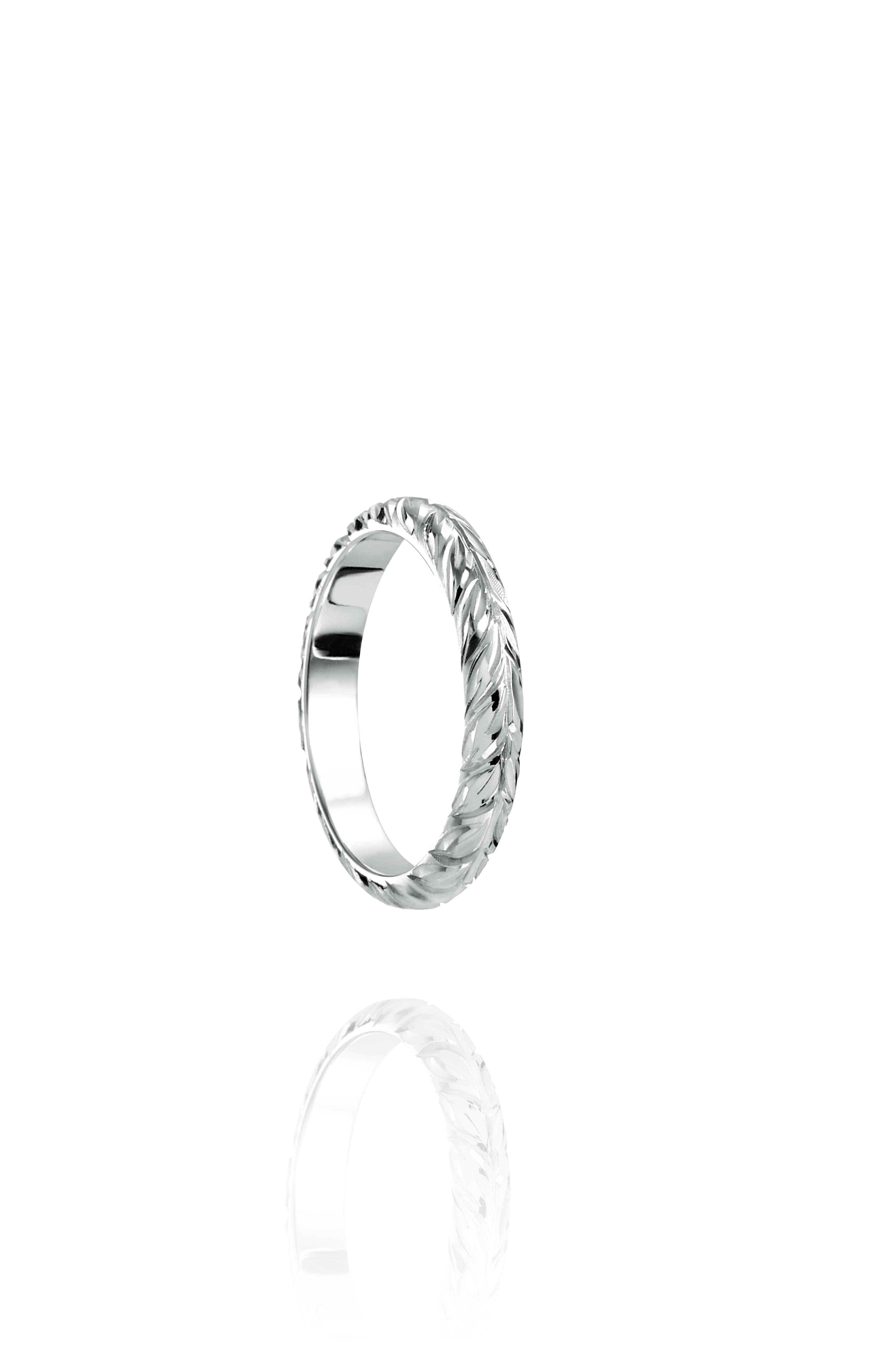 In this photo there is a white gold lei ring with hand engravings of a maile leaf.