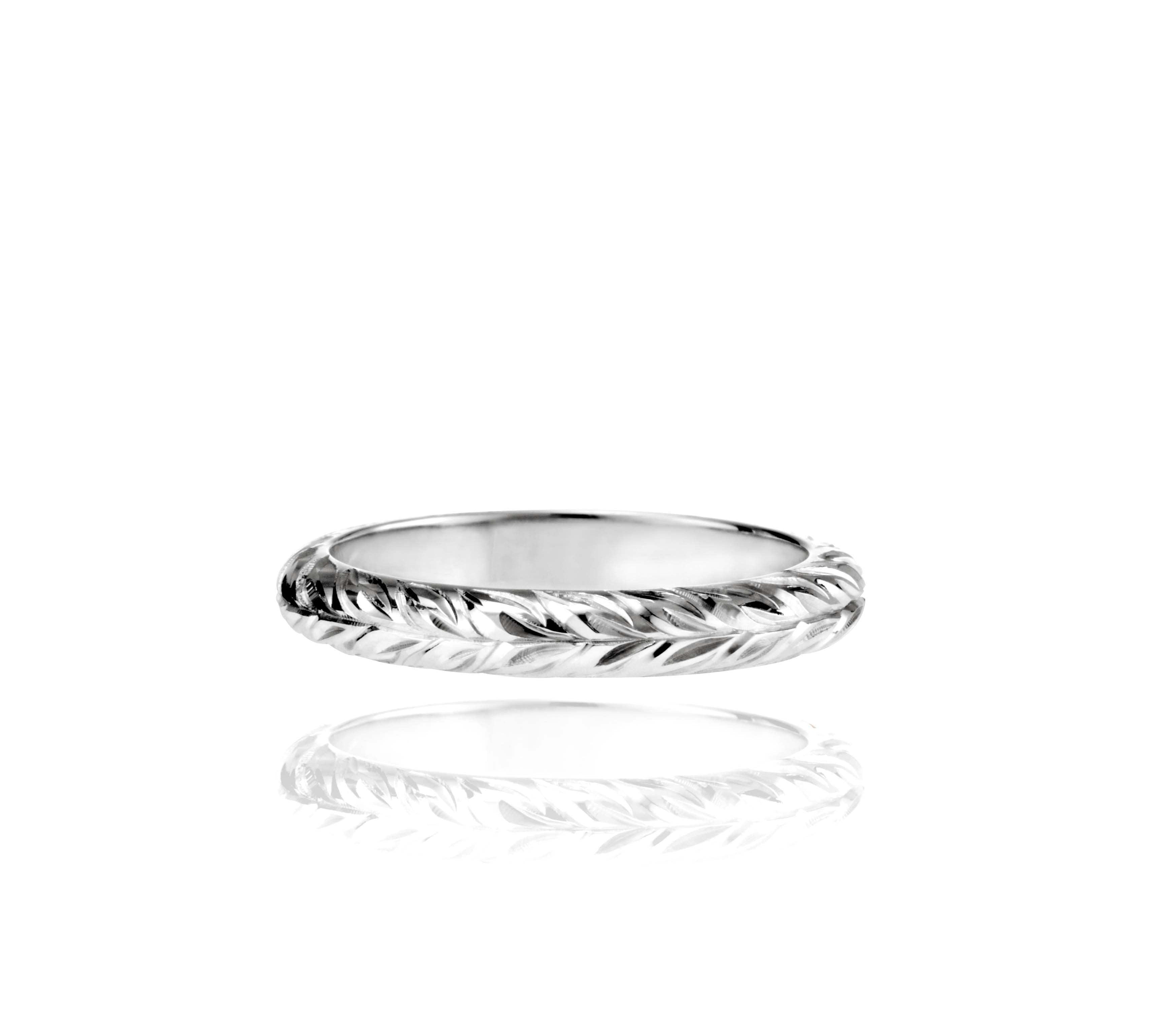 In this photo there is a white gold lei ring with hand engravings of a maile leaf.