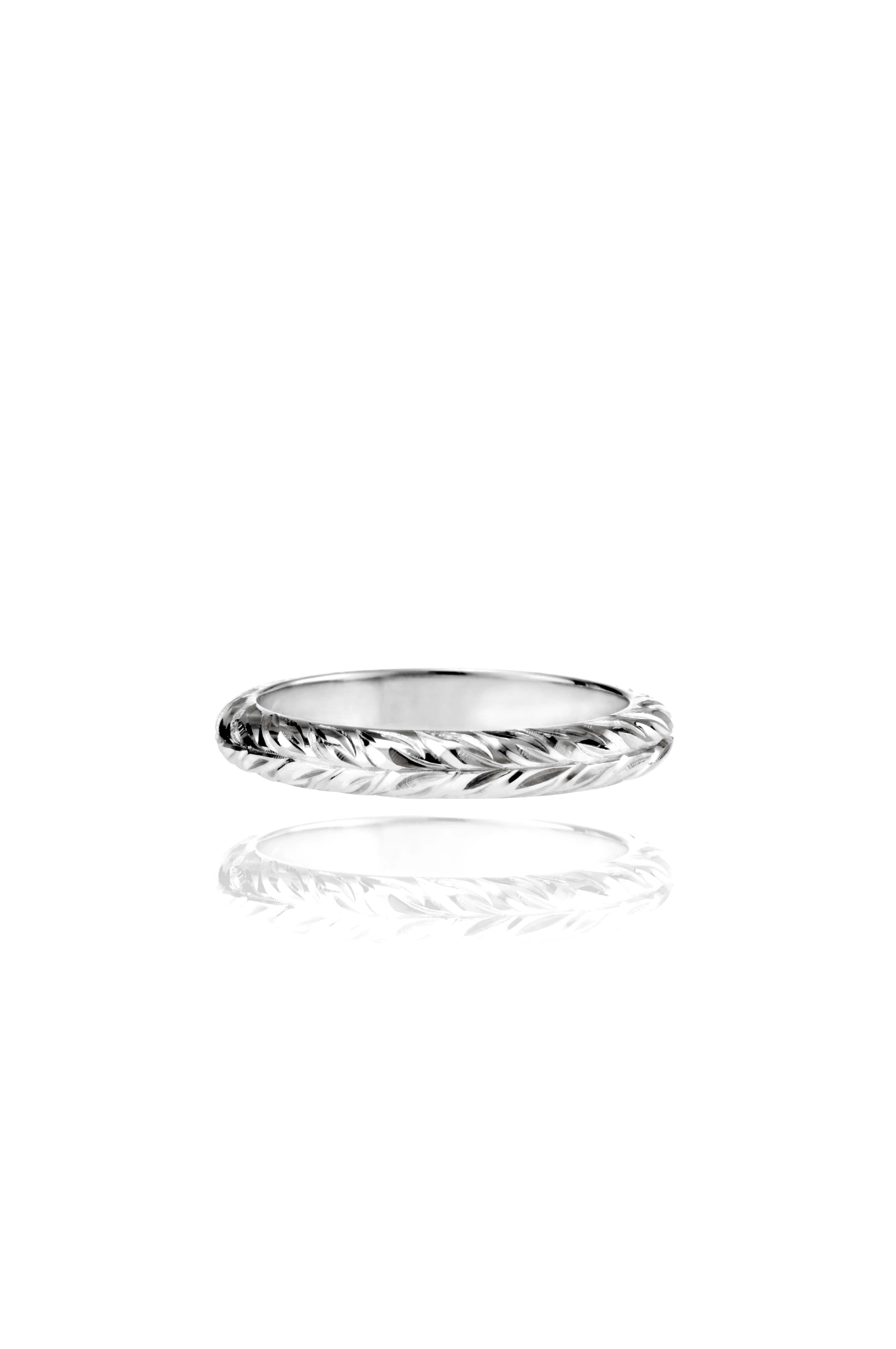 In this photo there is a white gold lei ring with hand engravings of a maile leaf.
