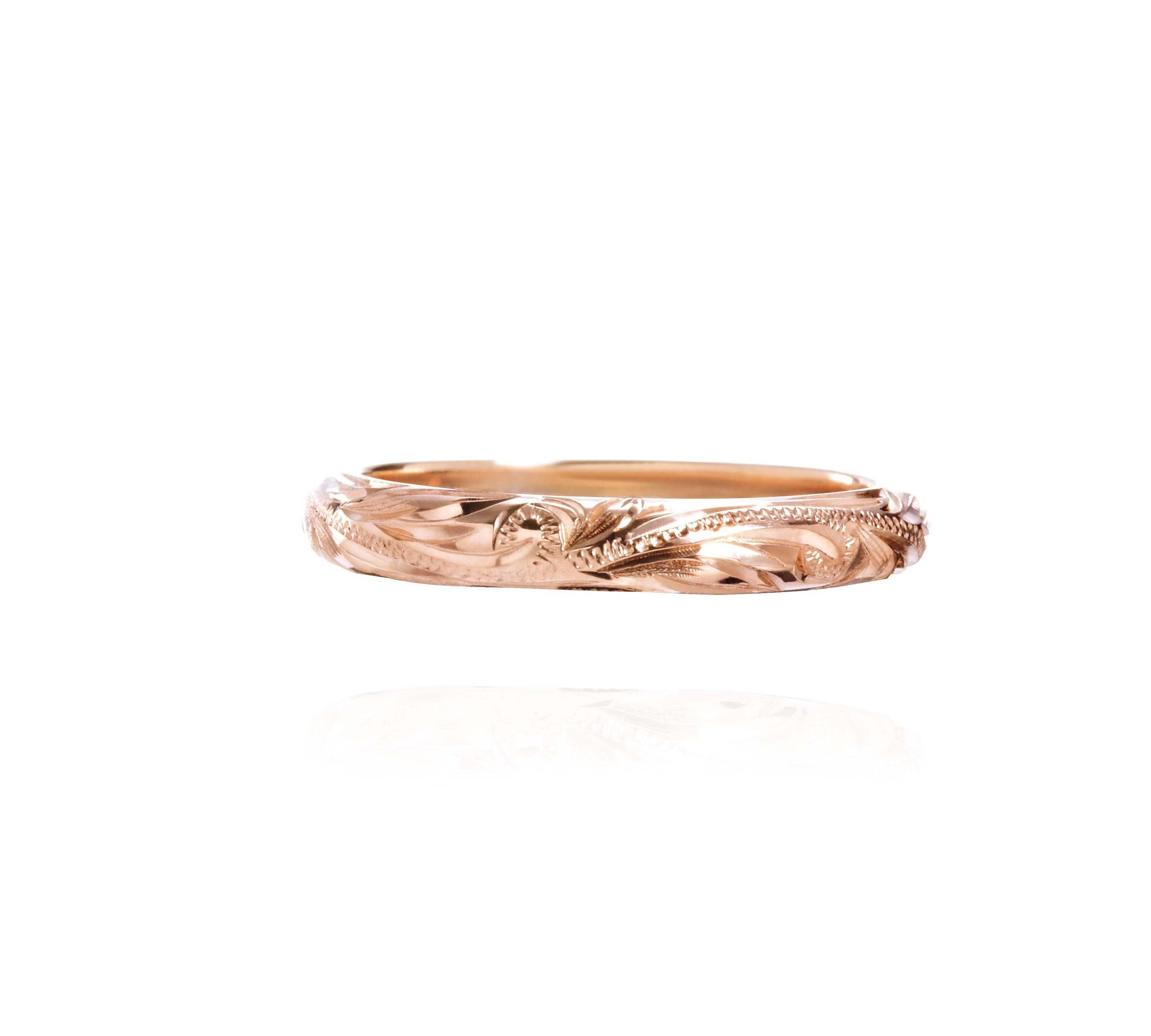 The picture shows a 14K rose gold infinity ring with hand-engraved detailing.