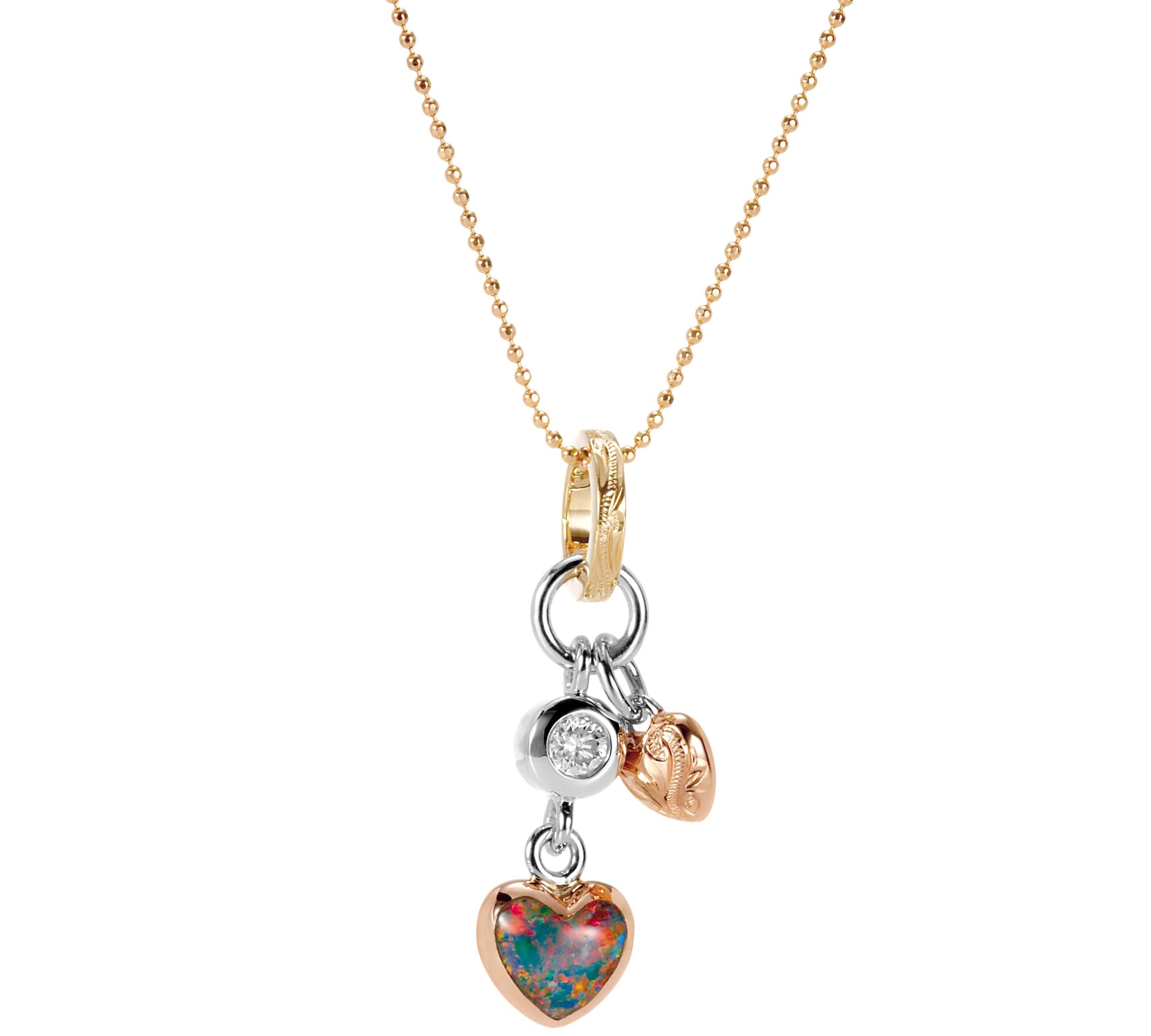 The picture shows a 14K yellow, white, and rose gold opal two-heart charm pendant with hand engravings and a diamond.