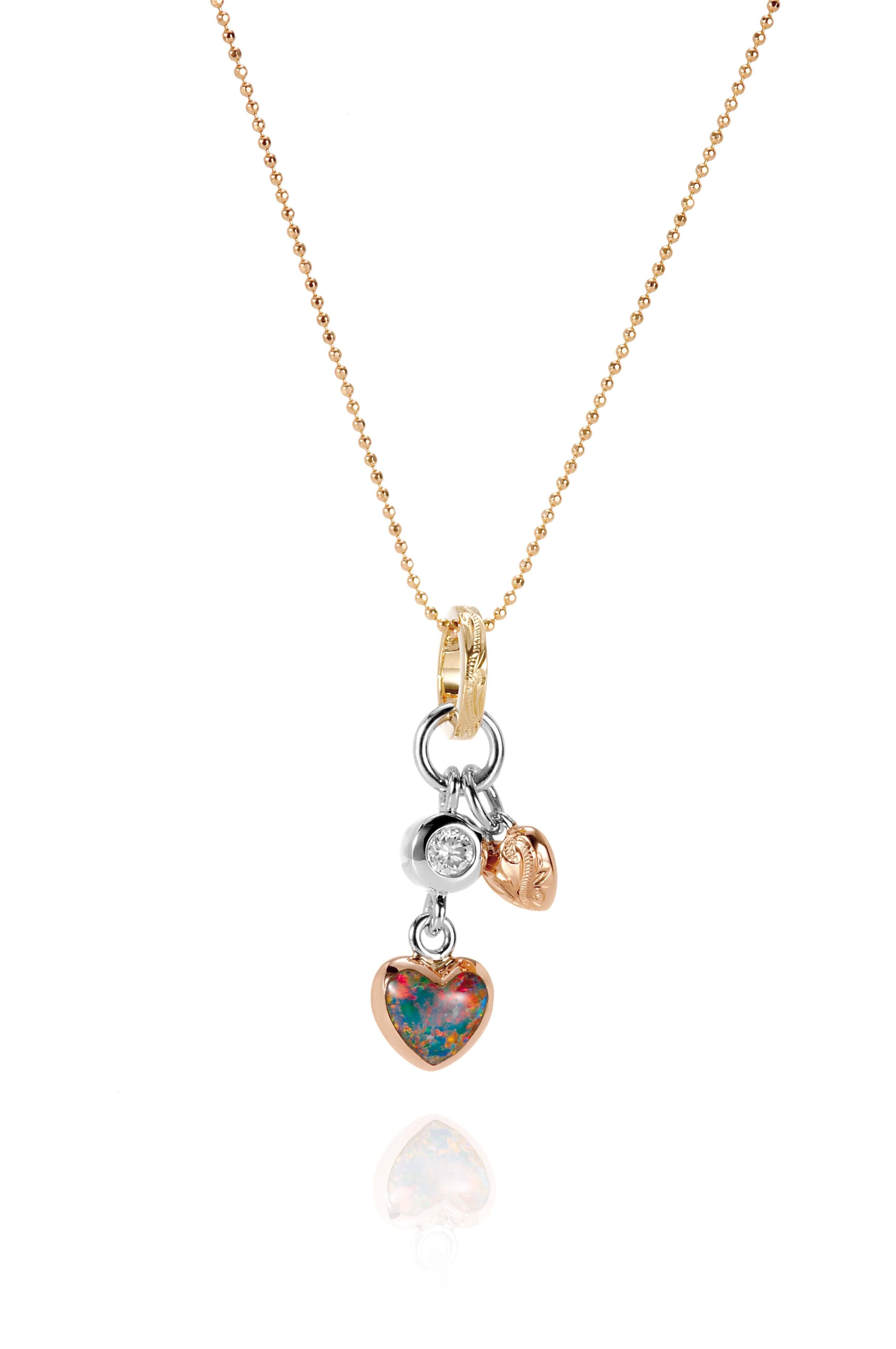 The picture shows a 14K yellow, white, and rose gold opal two-heart charm pendant with hand engravings and a diamond.