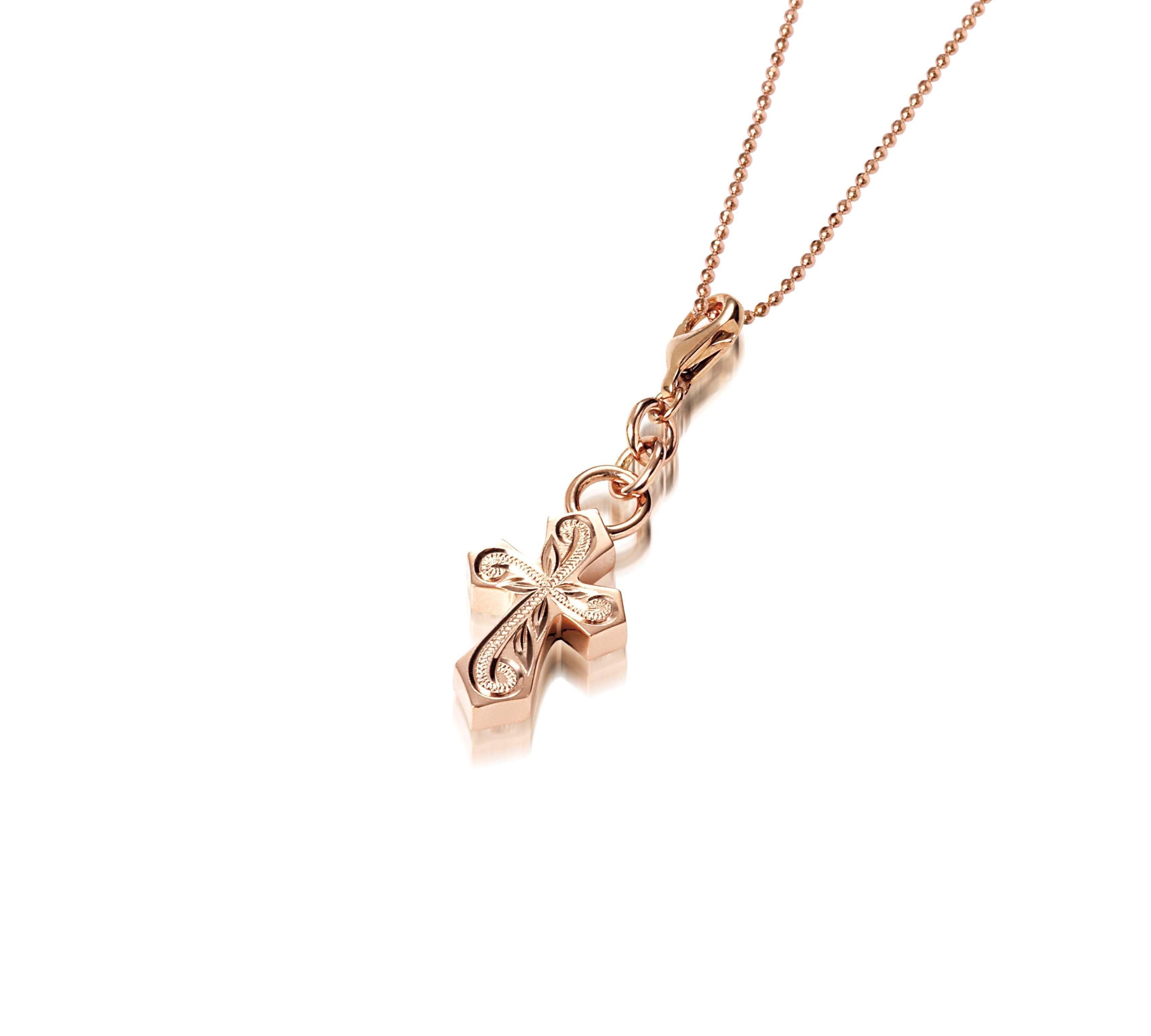 The picture shows a 14K rose gold pointed cross charm with hand-engraved detailing.