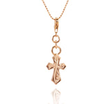 The picture shows a 14K rose gold pointed cross charm with hand-engraved detailing.