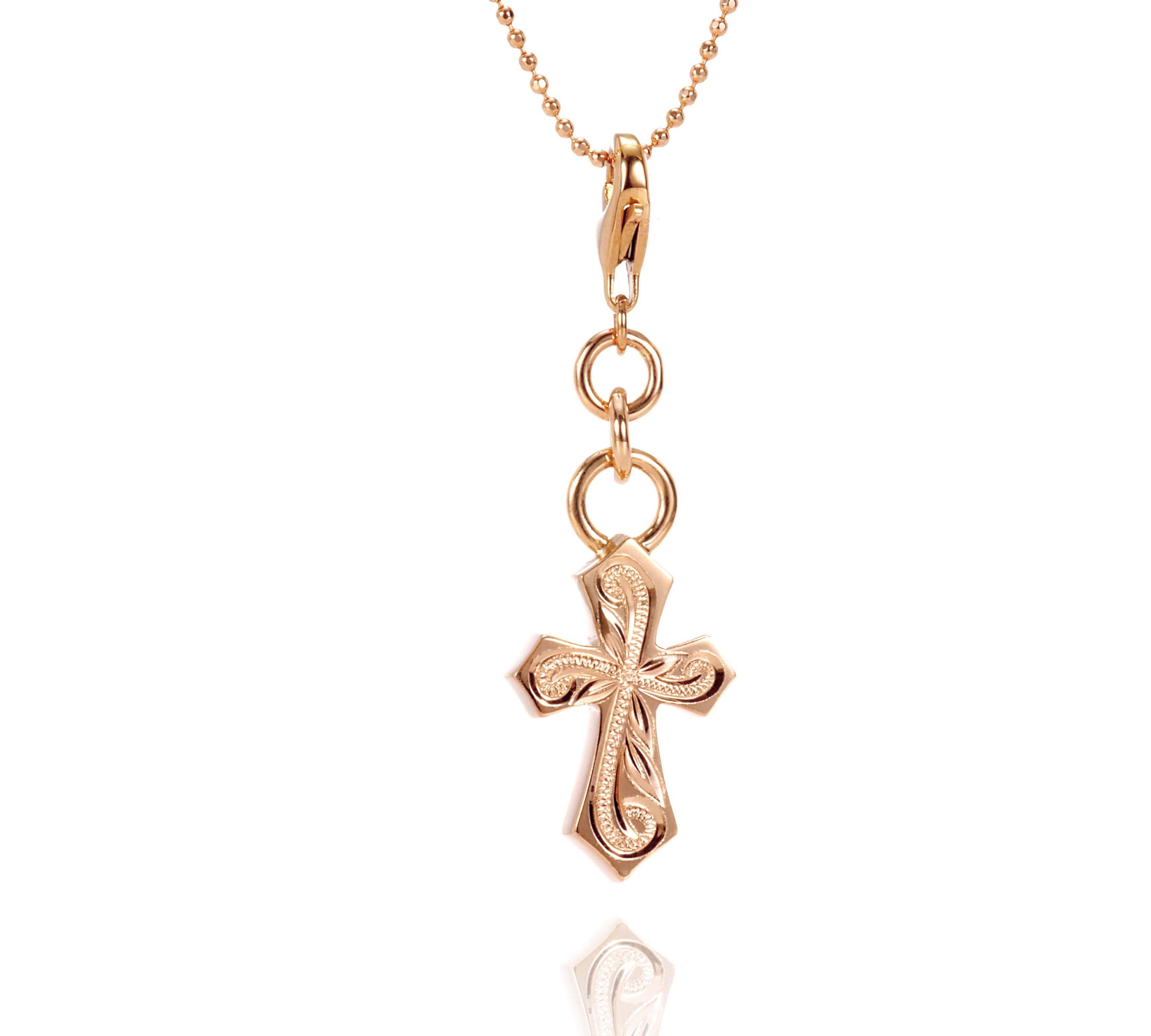 The picture shows a 14K rose gold pointed cross charm with hand-engraved detailing.