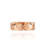 In this picture there is a rose gold cut out ring with hand engravings including flowers and scrolls.