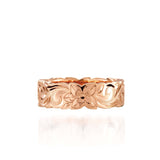 In this picture there is a rose gold cut out ring with hand engravings including flowers and scrolls.
