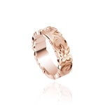 In this picture there is a rose gold cut out ring with hand engravings including flowers and scrolls.