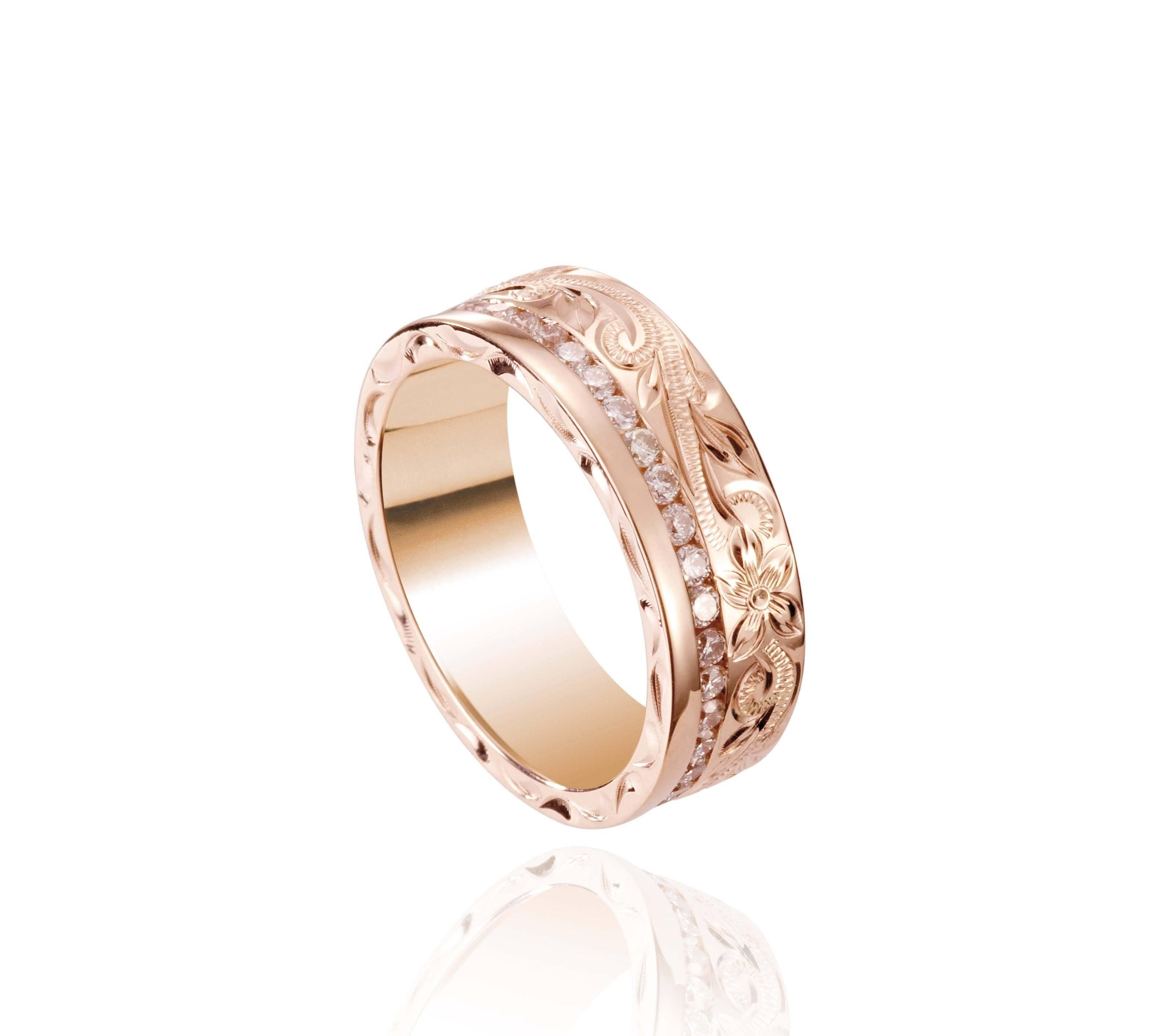 In this photo there is a rose gold ring with diamonds and hand engravings that include a flower and scroll.