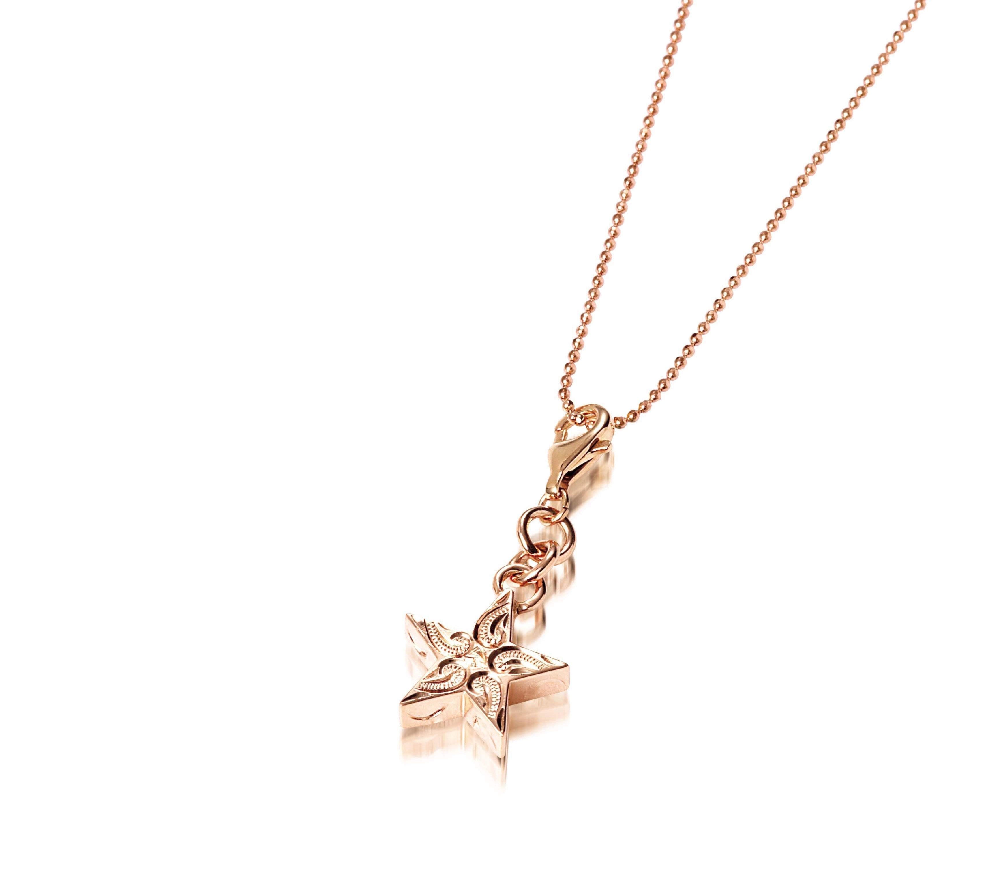 The picture shows a 14K rose gold star charm with paisley hand engravings.