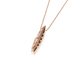 In this photo there is a rose gold surfboard pendant with diamonds and hand engravings.
