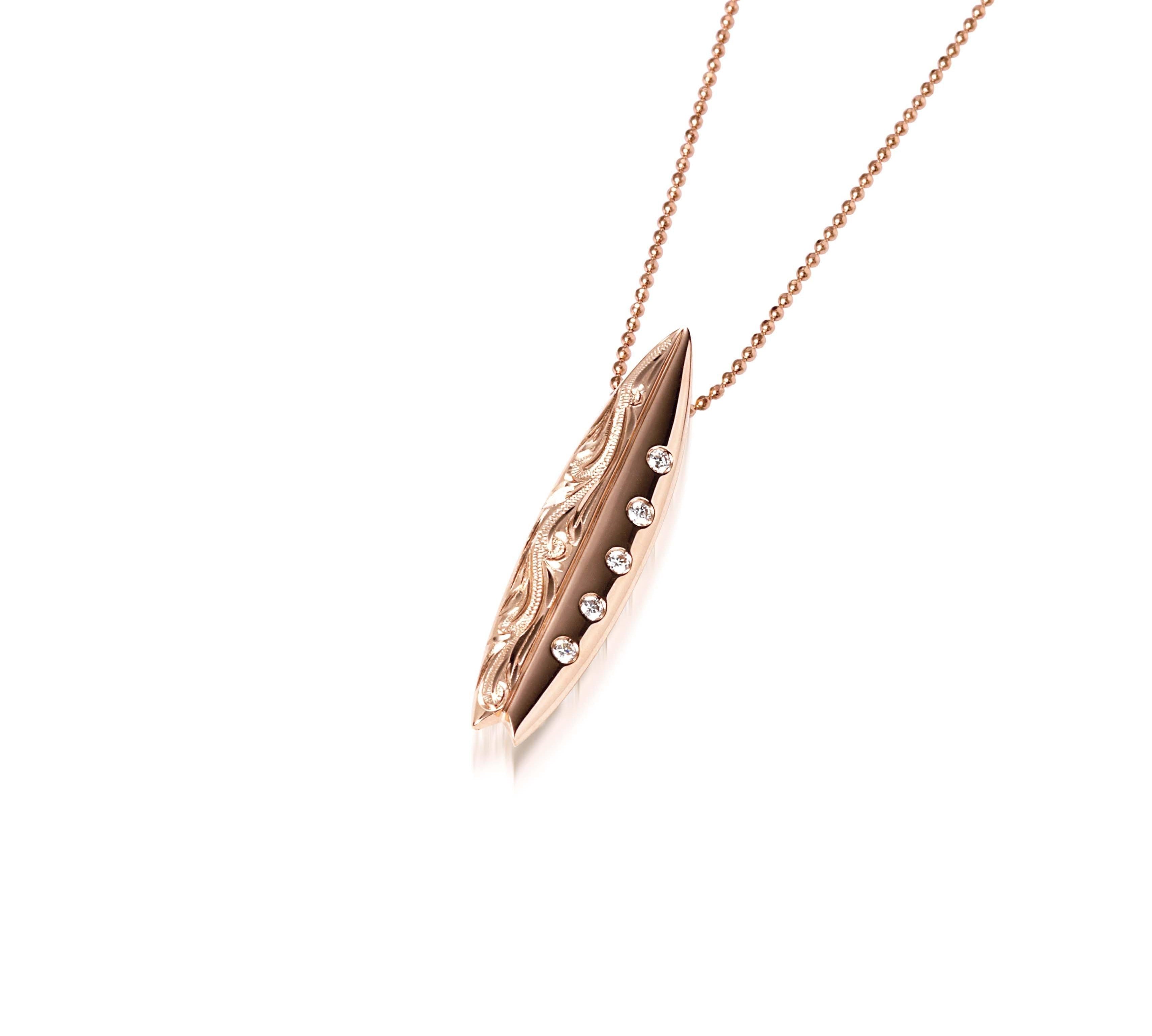 In this photo there is a rose gold surfboard pendant with diamonds and hand engravings.