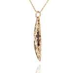 In this photo there is a yellow gold surfboard pendant with an opal cross and hand engravings.