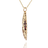 In this photo there is a yellow gold surfboard pendant with an opal cross and hand engravings.