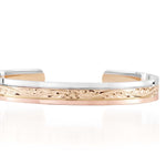 The picture shows a 14K white, yellow, and rose gold tri-color bangle with plumeria engraving.