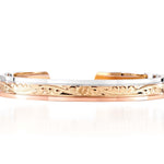 The picture shows a 14K white, yellow, and rose gold tri-color bangle with scroll engraving.