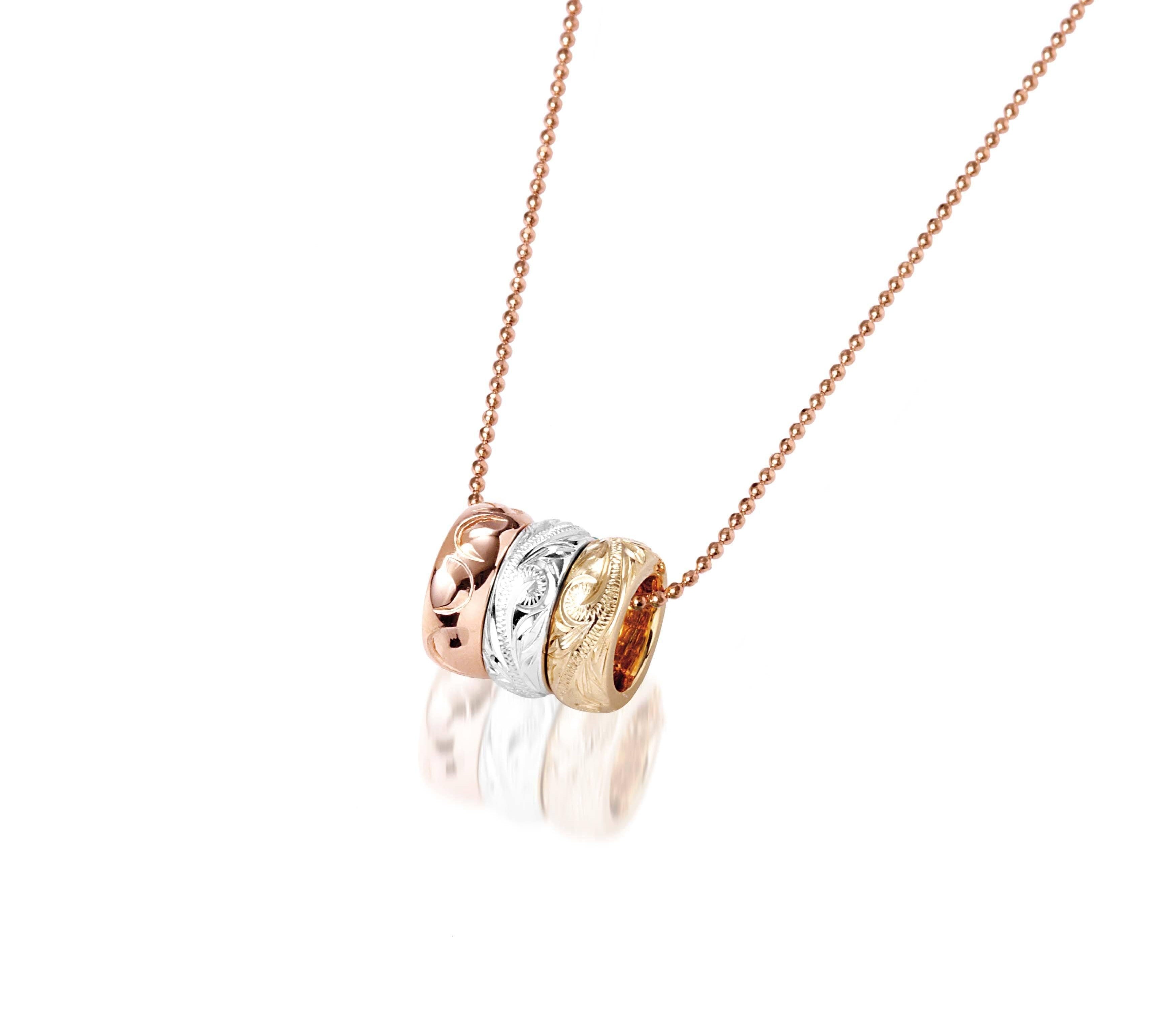 The picture shows a 14K rose, white, and yellow gold tricolor three ring pendant with hand engravings.