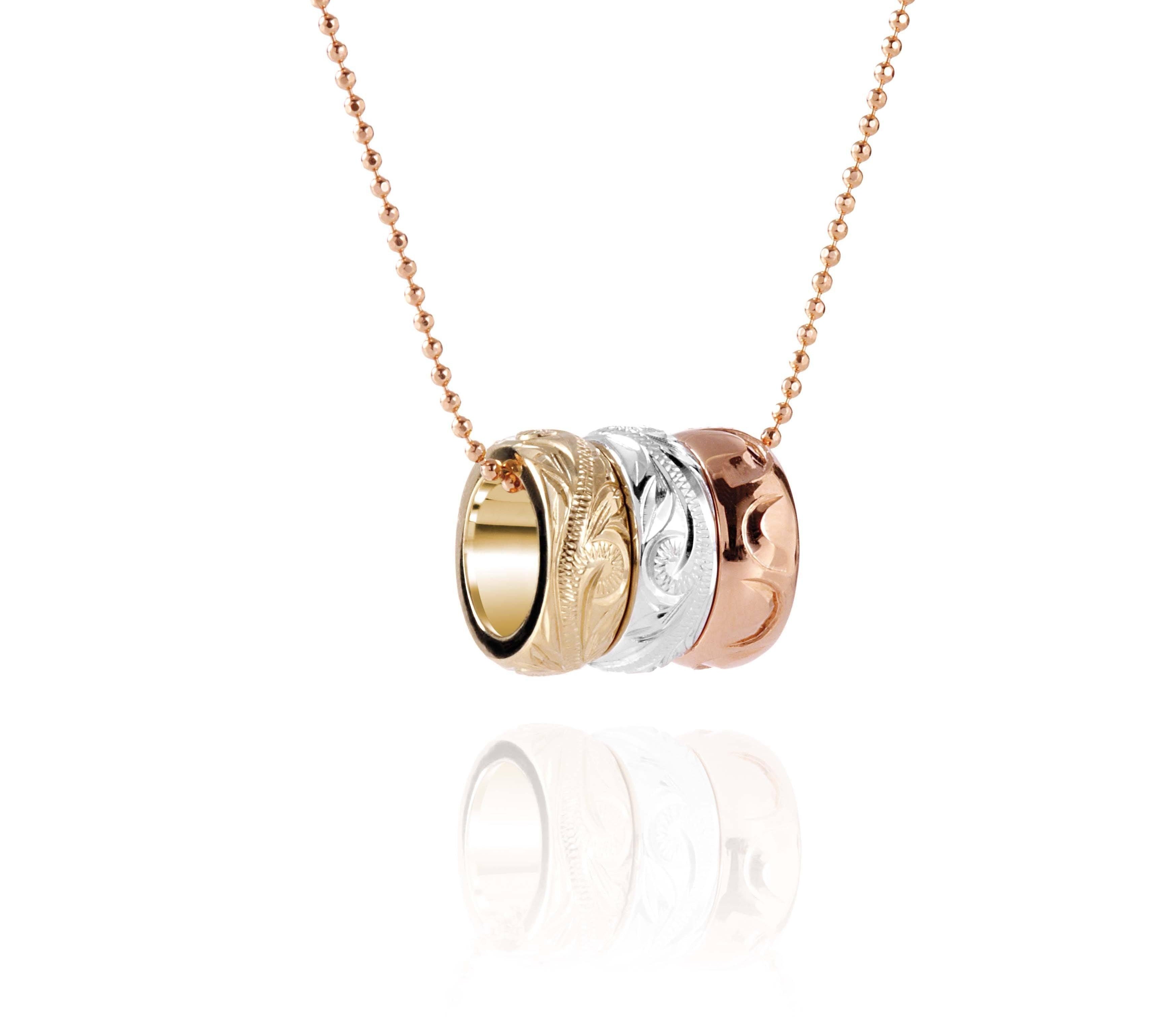The picture shows a 14K rose, white, and yellow gold tricolor three ring pendant with hand engravings.