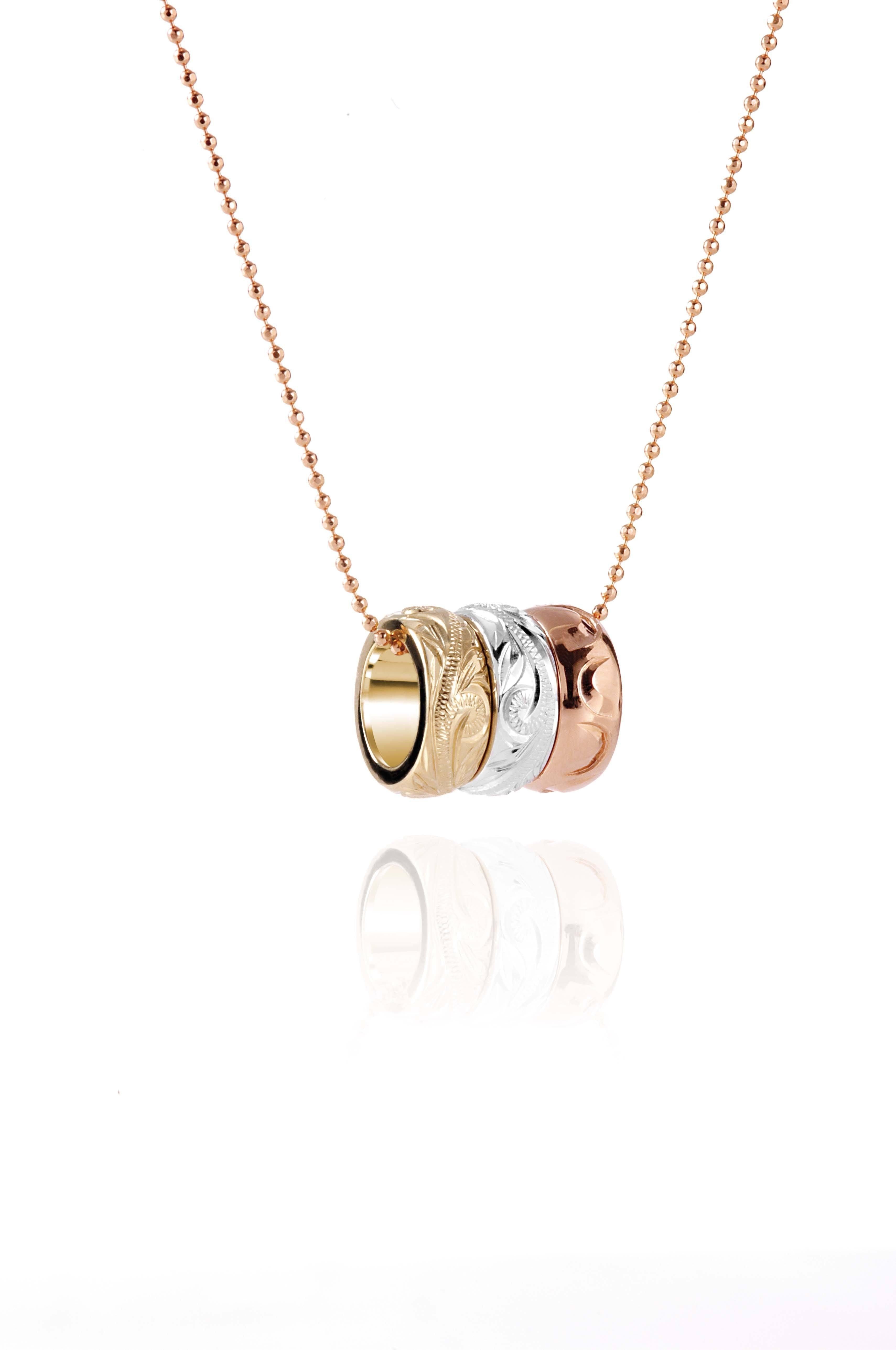The picture shows a 14K rose, white, and yellow gold tricolor three ring pendant with hand engravings.