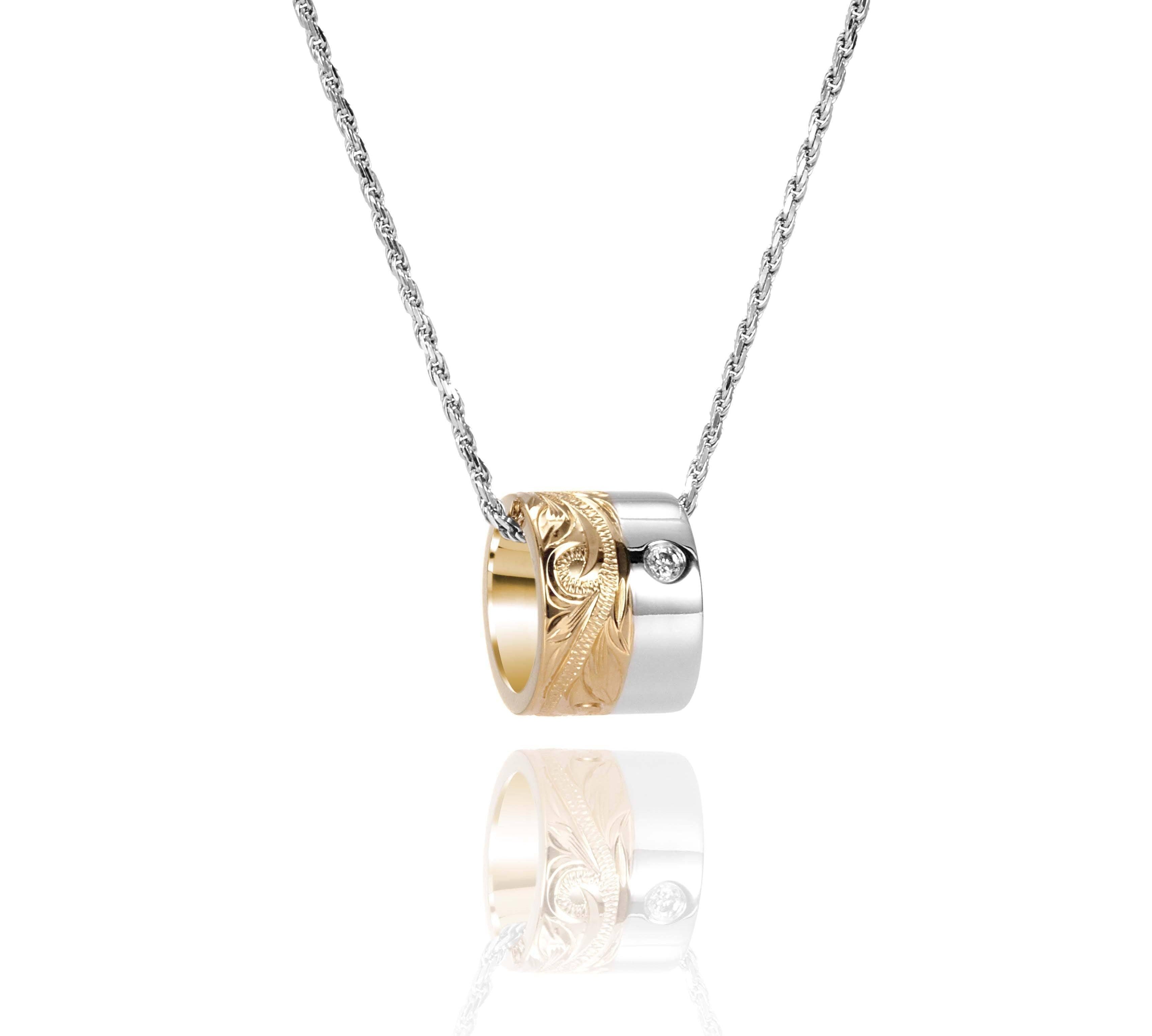 This picture shows a 14k yellow and white gold two-tone barrel pendant with hand engravings and a diamond.