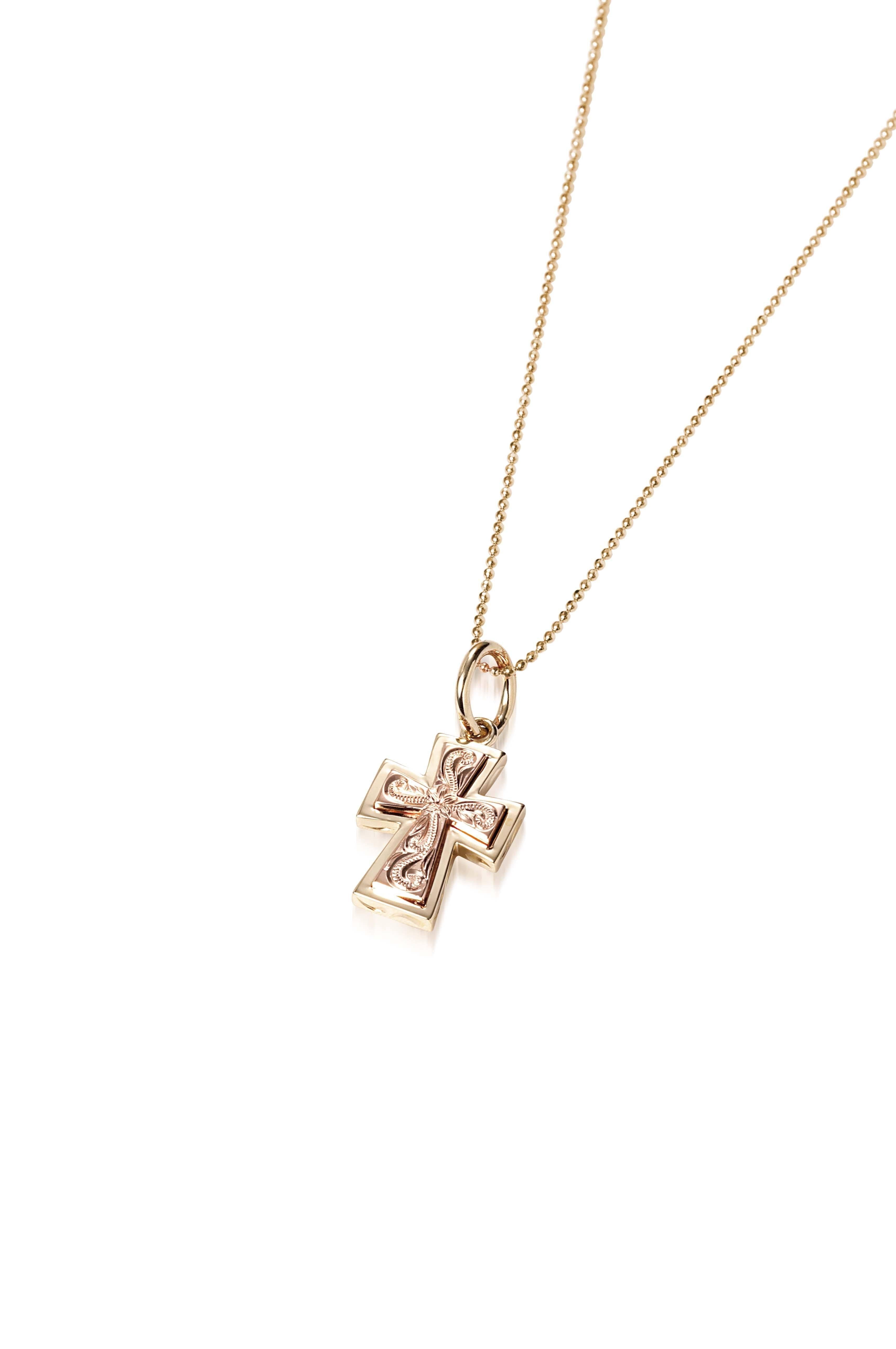 The picture shows a 14K yellow and rose gold two-tone cross pendant with hand engravings.