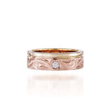 The picture shows a 14K yellow and rose gold two-tone wave channel 6mm ring with a diamond and hand-engravings.