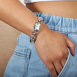Sterling silver bangle featuring a Abalone shell oval, and inlayed topaz, worn by a model.