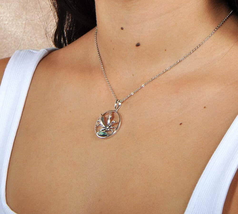 A model wearing the Sterling silver pendant designed to look like a Nene bird flying featuring Abalone.
