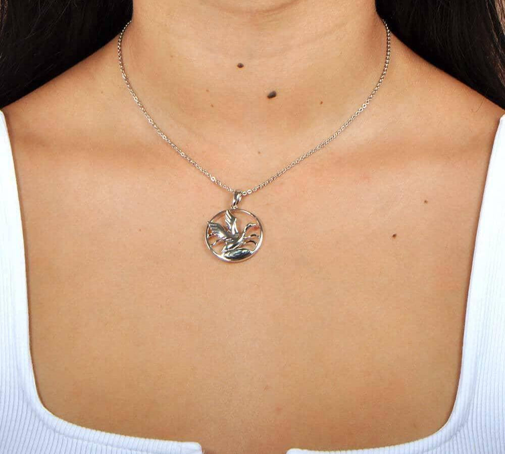A model wearing the Sterling silver pendant designed to look like a Nene bird flying featuring Abalone.