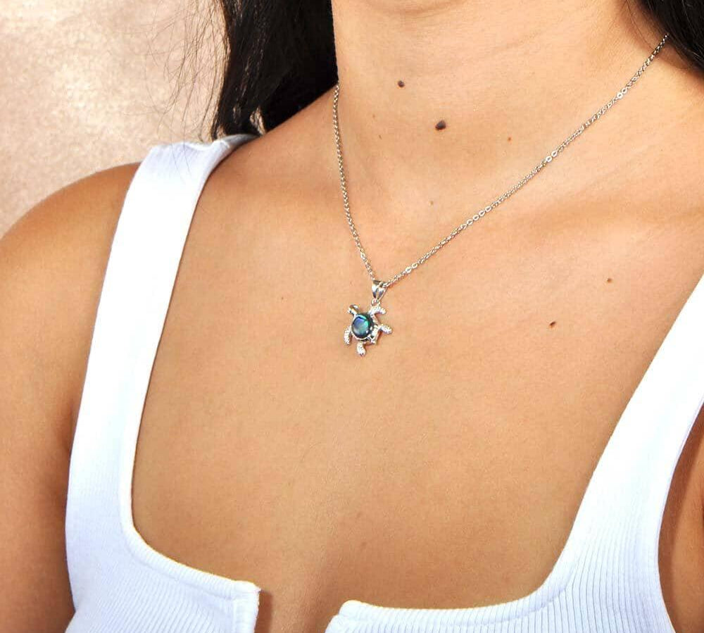 A model wearing a Sterling Silver Sea Turtle pendant, featuring and Abalone Shell. 