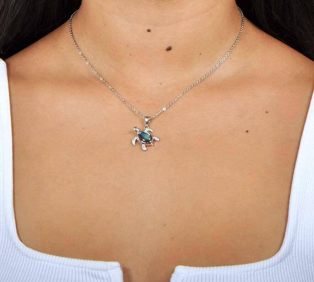 A model wearing a Sterling Silver Sea Turtle pendant, featuring and Abalone Shell. 