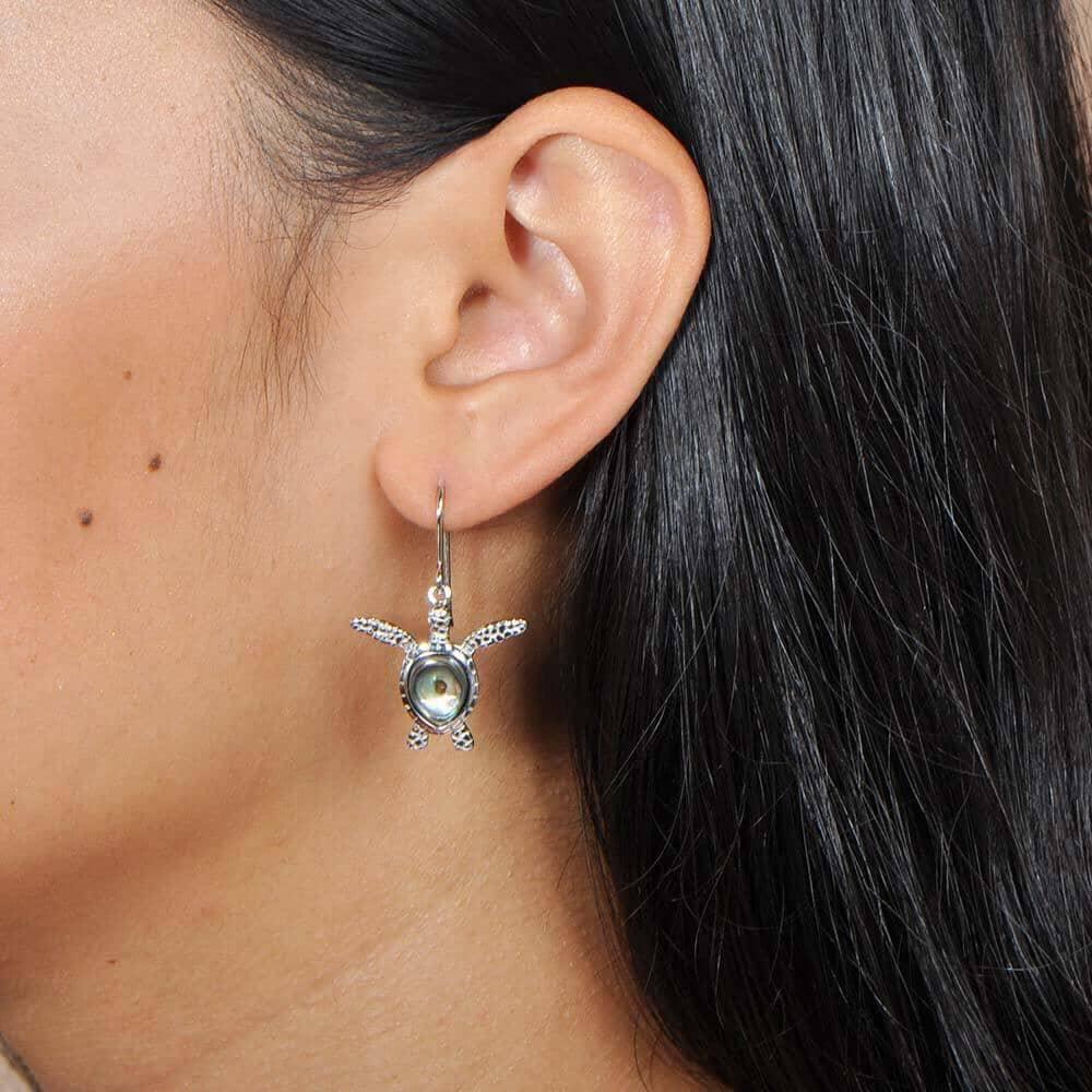 Abalone and sterling silver sea turtle hook earrings worn by a model
